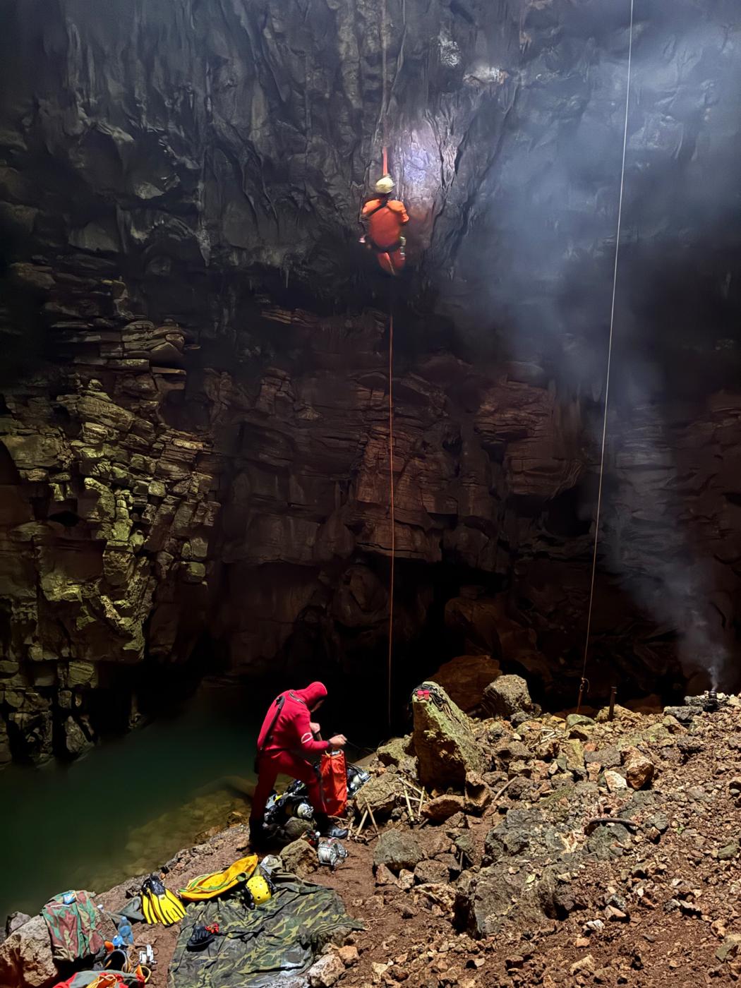 Caver descending on a rope into a deep cave