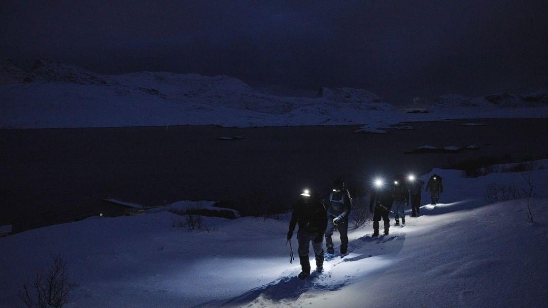 Team hiking with headlamps in the polar night