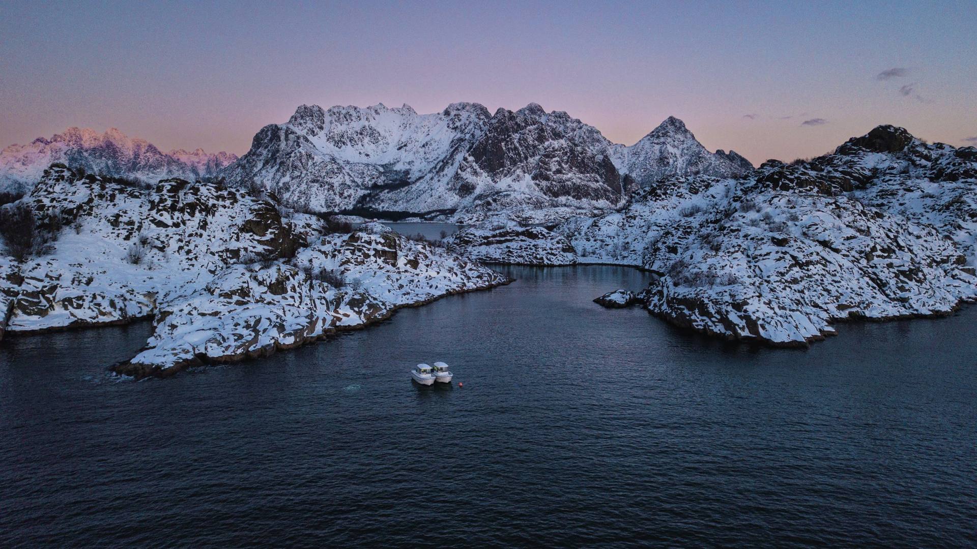 Two boats in a snowy fjord at dusk